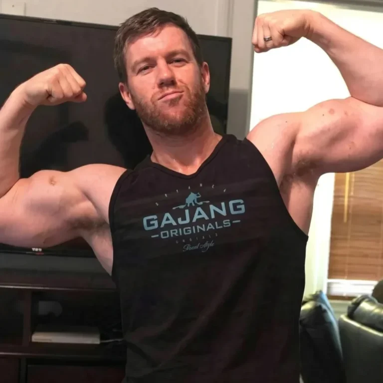 Muscular male fitness trainer flexing his biceps proudly for members at Feel Good Fitness.