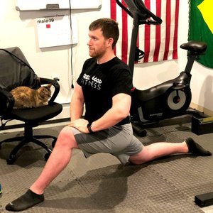 Man performing a deep lunge stretch during a home workout session with Feel Good Fitness.
