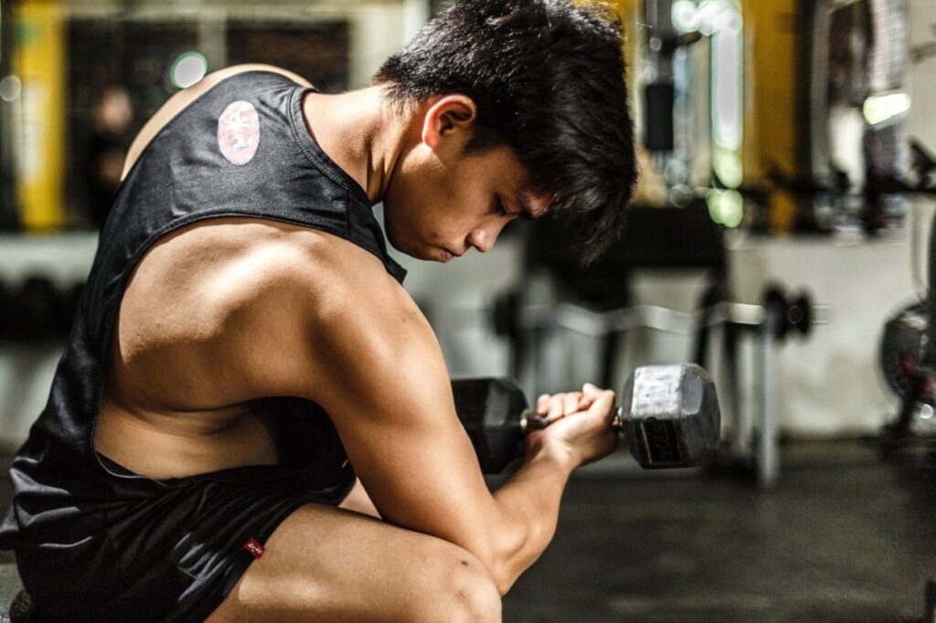 Focused athlete lifting dumbbells during an indoor strength training workout session at Feel Good Fitness.